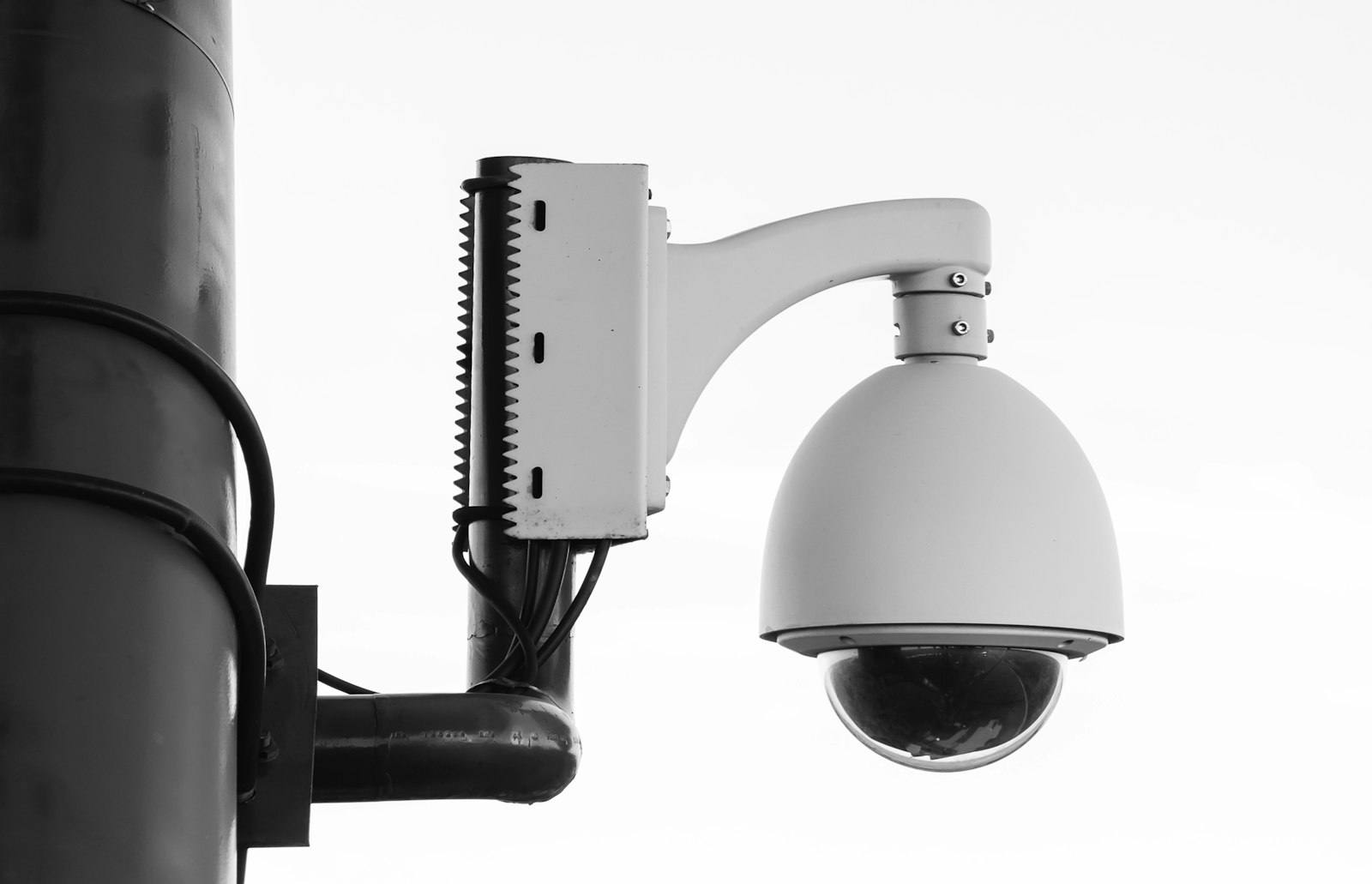 A white dome security camera on a bracket fixed to a pole